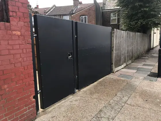 Black steel double gates closing off a brick alley