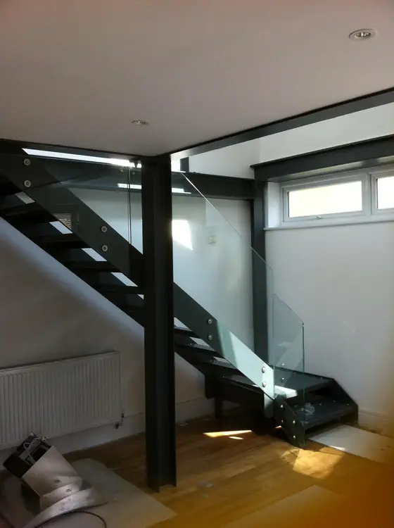 A black steel staircase with a glass panel up the side of it