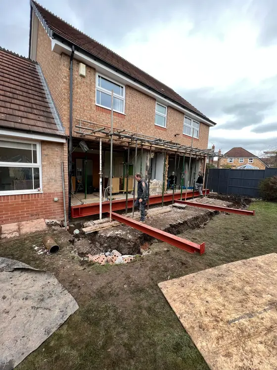 A red steel beam across the back of a two storey house, propped and scaffolded