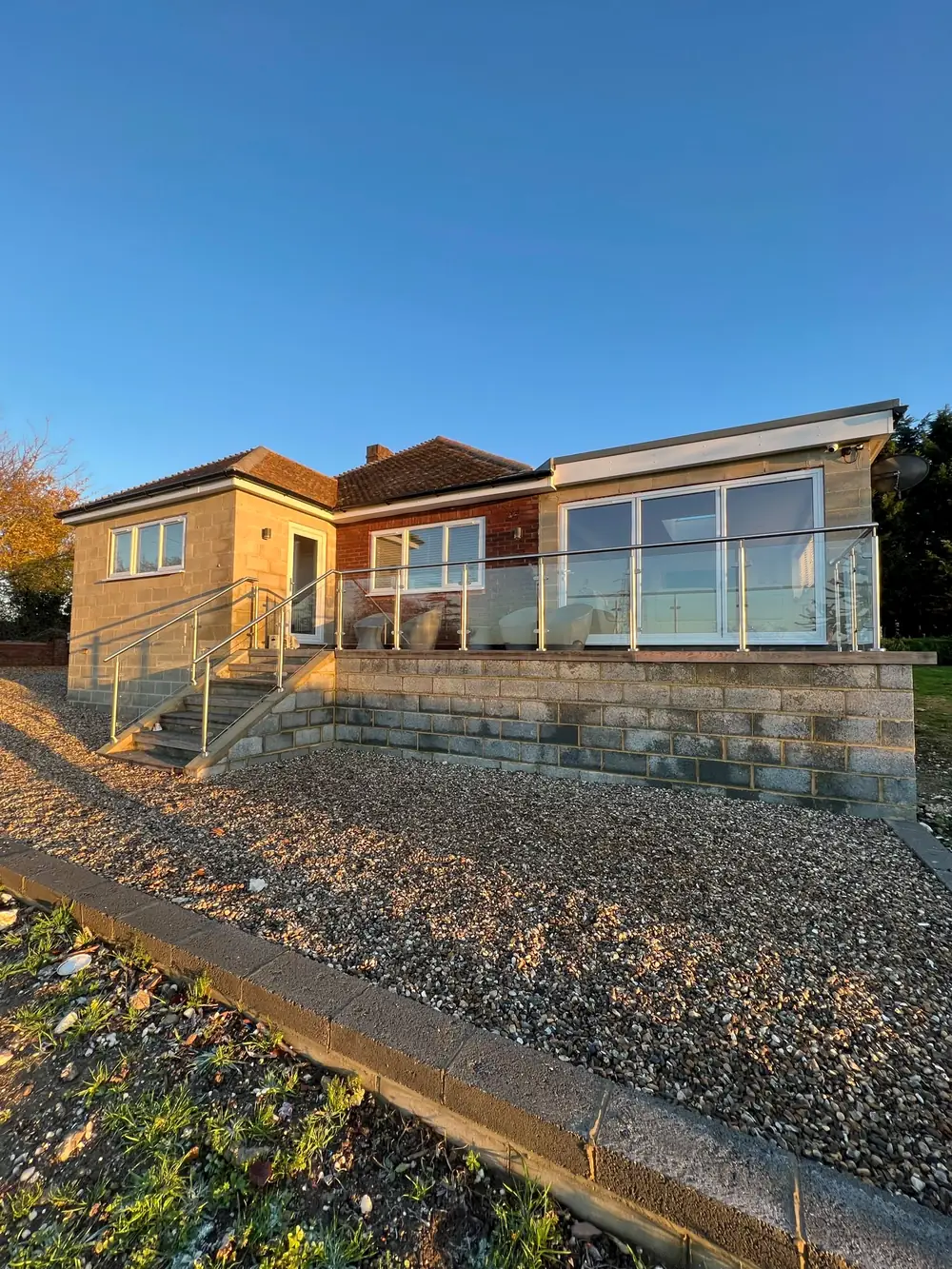 A glass and stainless steel rail around a raised deck