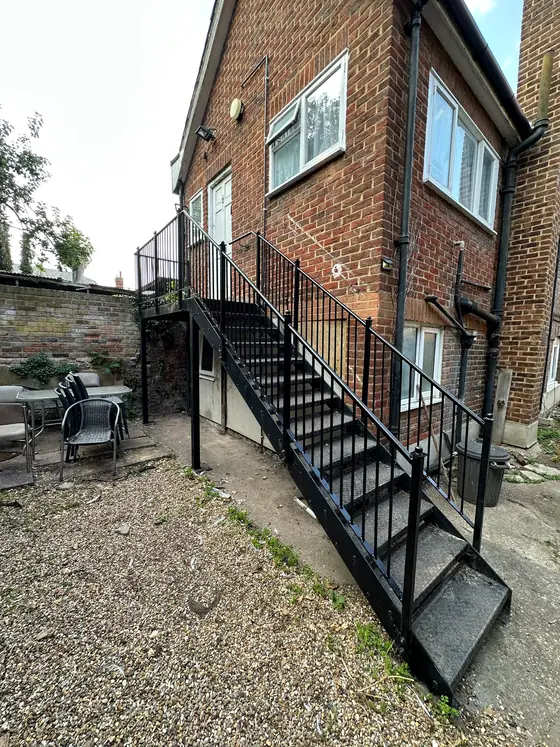 A black steel staircase and landing on the outside of a brick house
