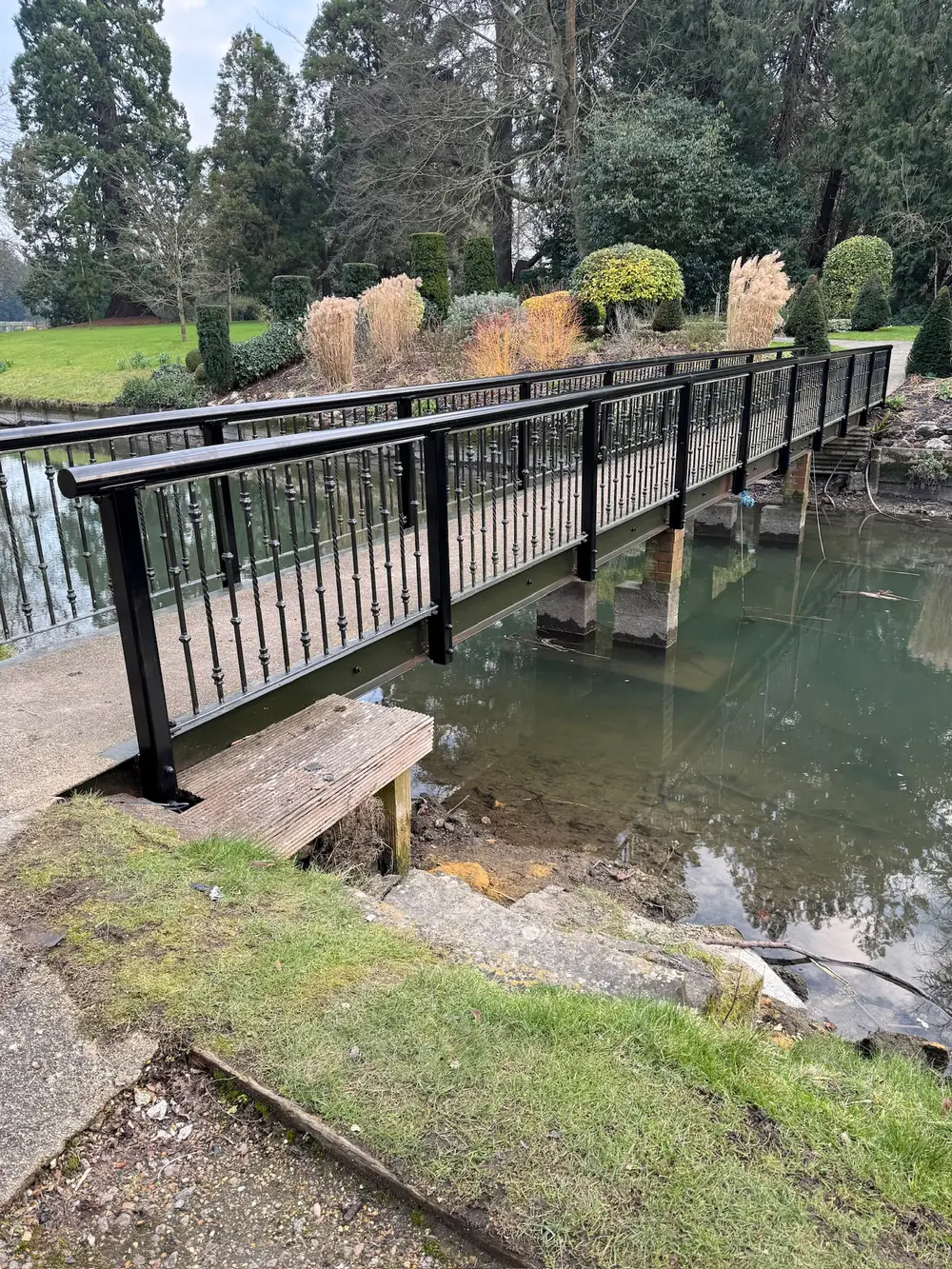 The steel footbridge and its handrail crossing the lake