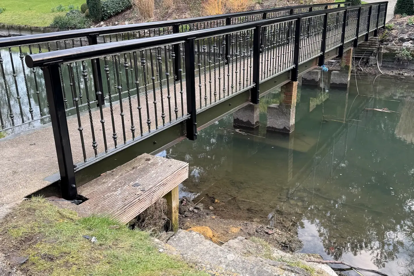 The steel footbridge and its handrail crossing the lake