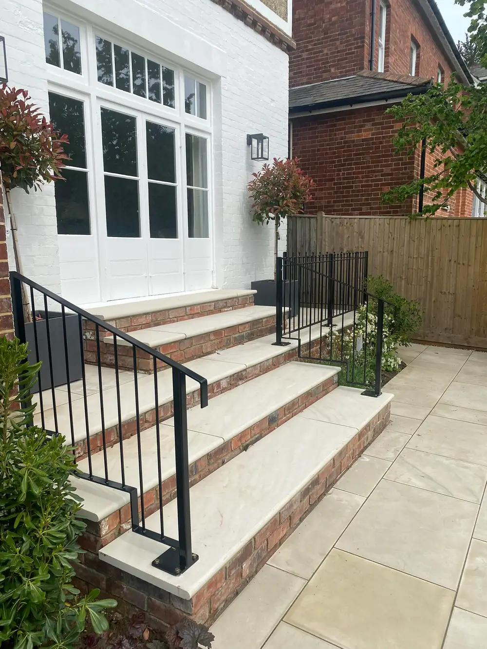 A black steel handrail on brick front steps