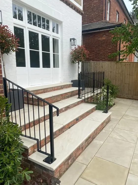 A black steel handrail on brick front steps