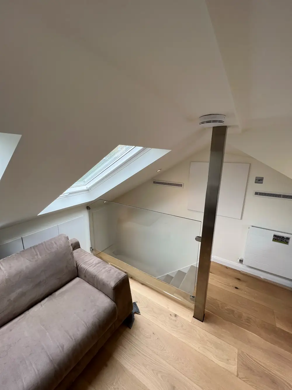 The same loft finished, with the steel post still there and a glass panel around the opening down to the stairs