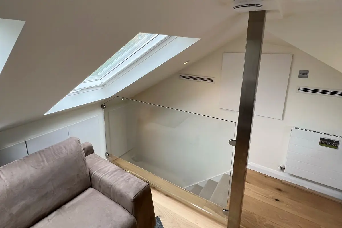 The same loft finished, with the steel post still there and a glass panel around the opening down to the stairs