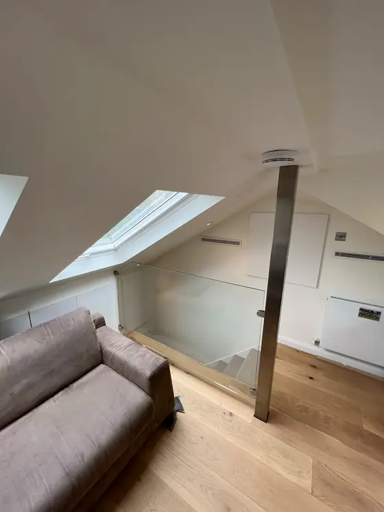 The same loft finished, with the steel post still there and a glass panel around the opening down to the stairs