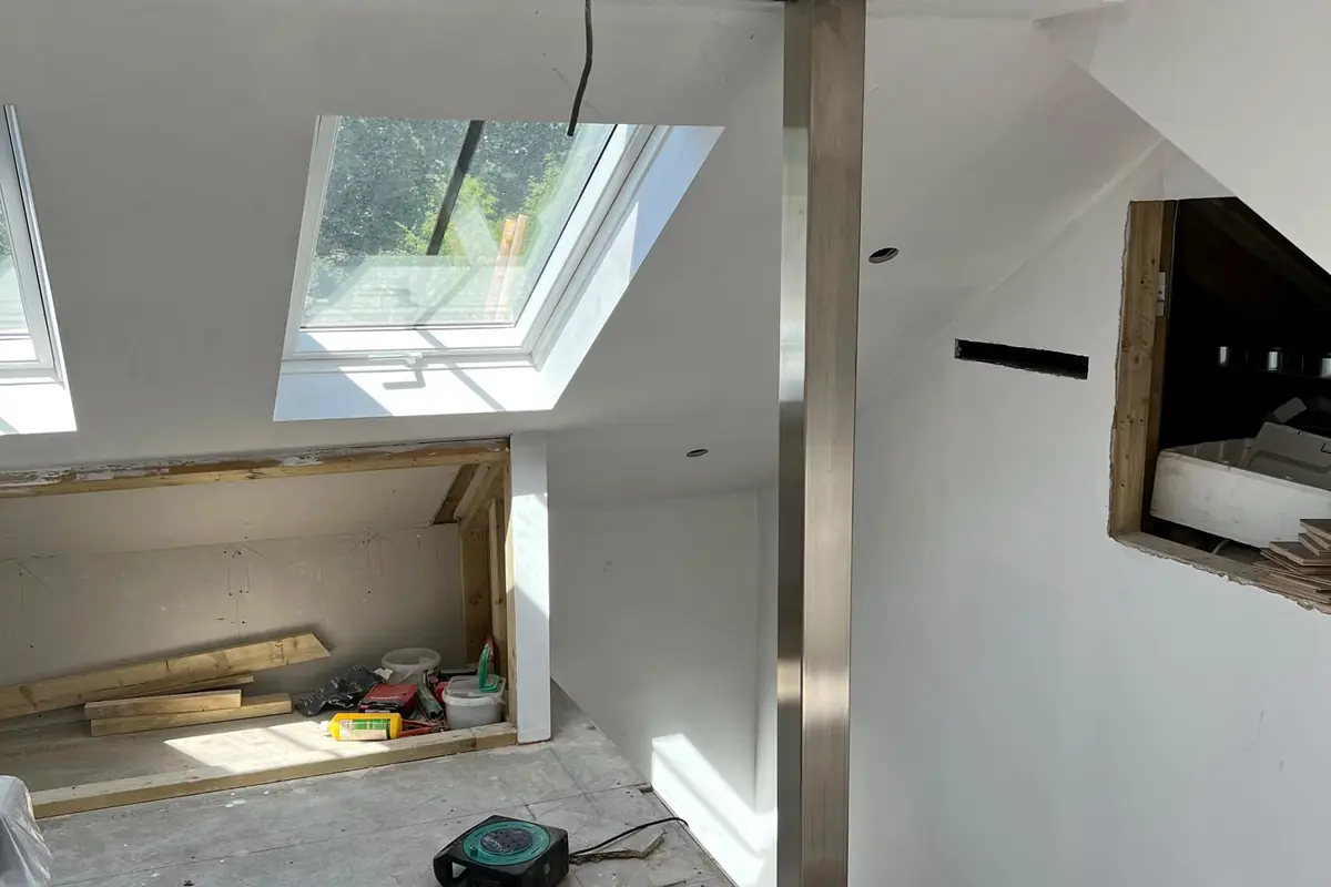 A loft part way through being converted, with a steel post standing floor to ceiling on a bare concrete floor