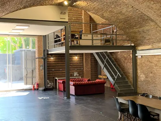 A steel floor built inside a brick arch, so one tall space becomes two levels