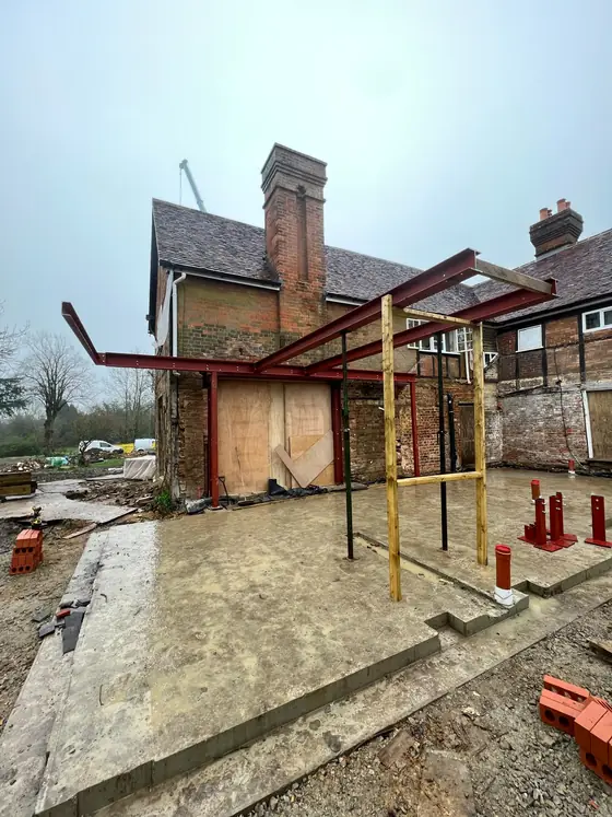 A red steel frame at the back of an old house