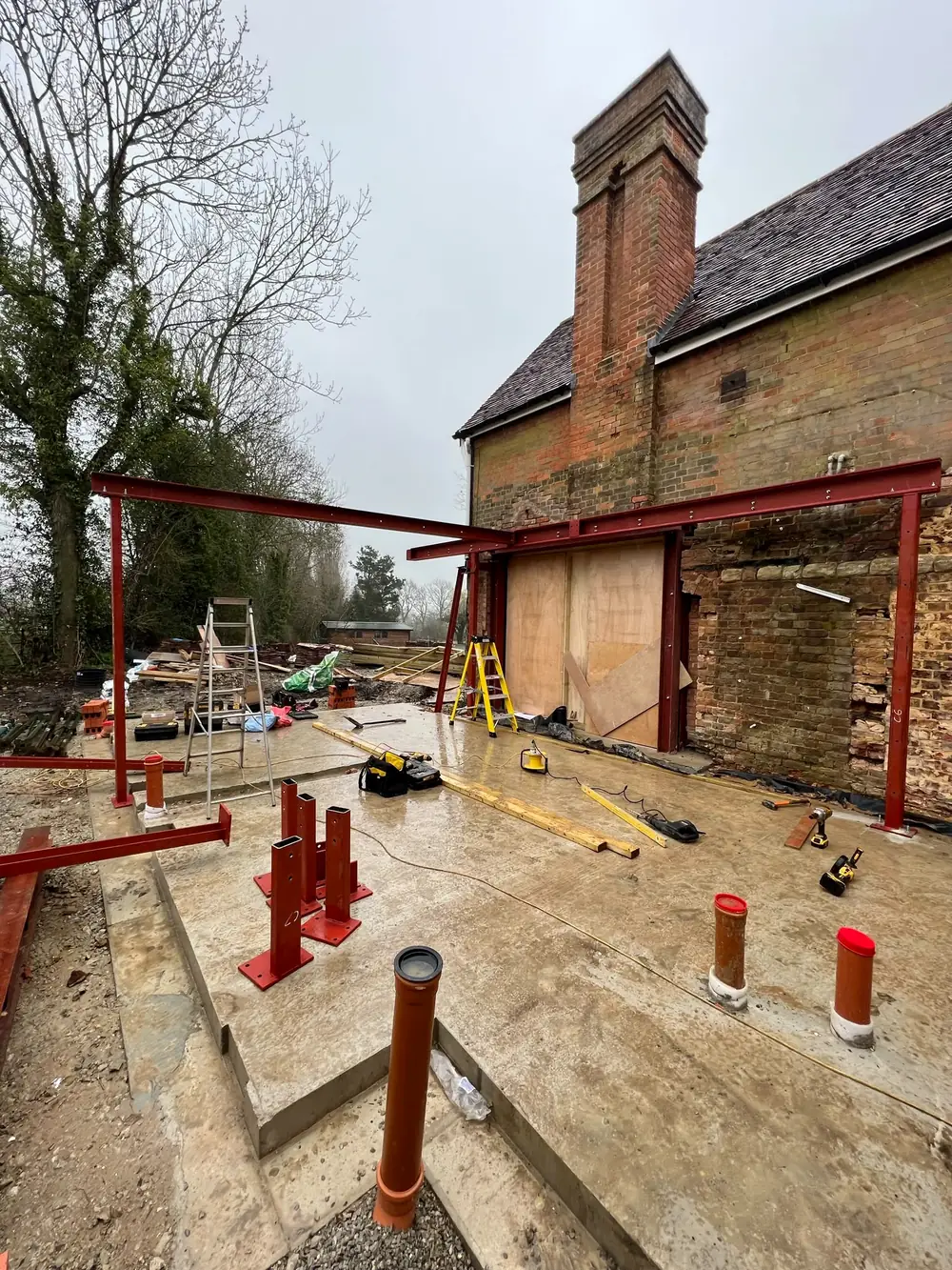 A red steel frame and adjustable steel legs at the back of an old house