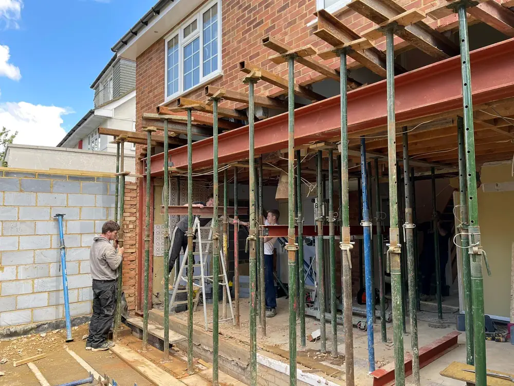 Steel legs and scaffolding holding up the back wall of a house while the work is done