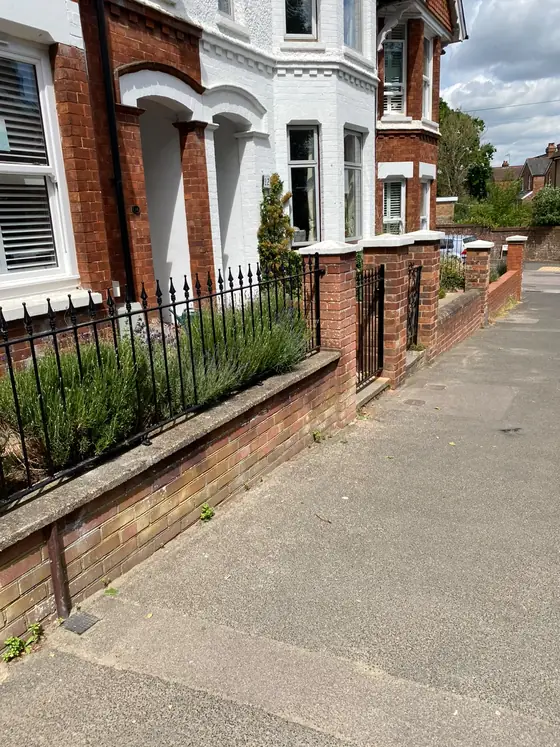 Black railings on a low brick wall along an old street