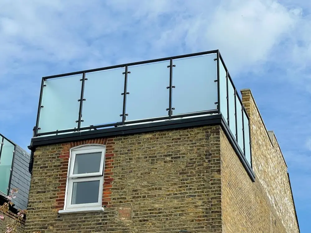 A glass rail with black posts around a roof terrace