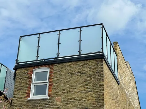 A glass rail with black posts around a roof terrace