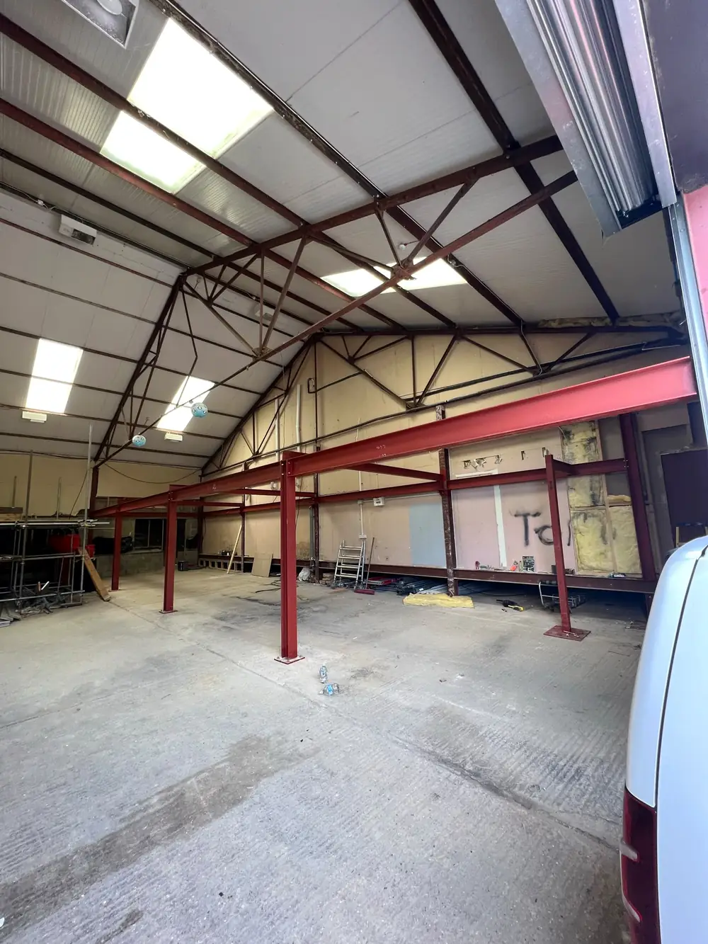 Red steel beams and posts carrying the roof of an industrial building