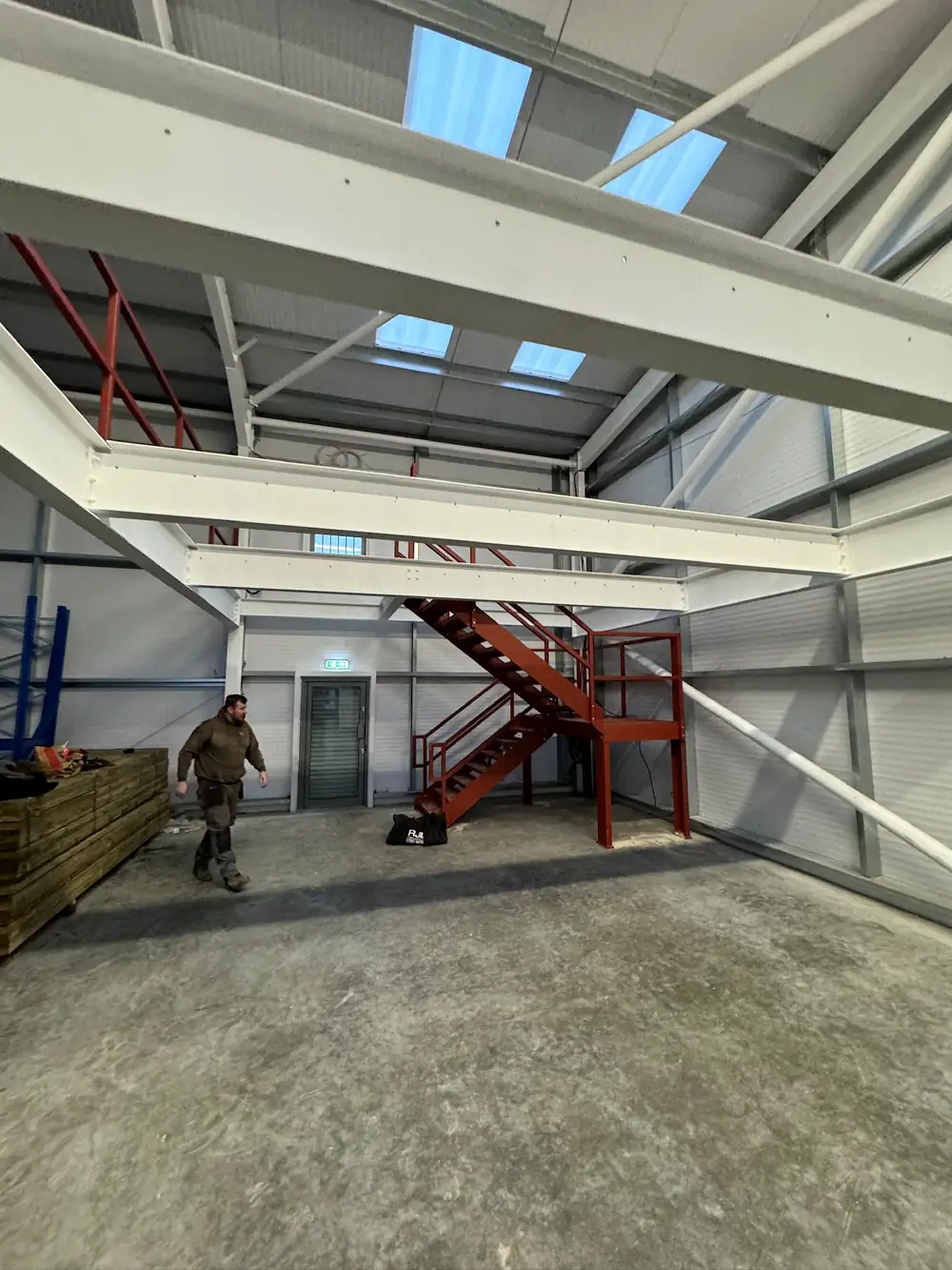 A white steel frame and a red steel staircase inside an industrial building
