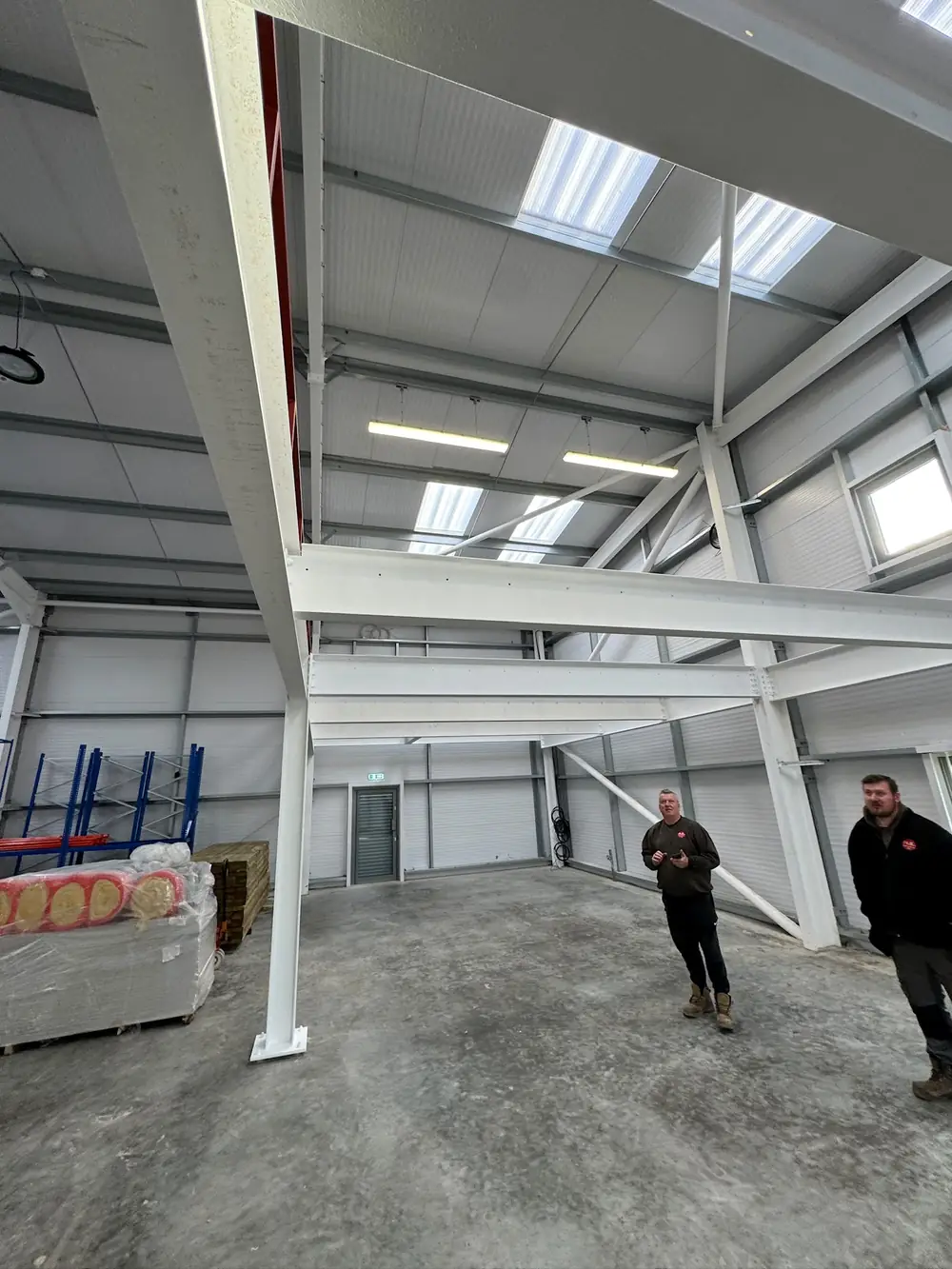 A white painted steel frame inside an industrial building
