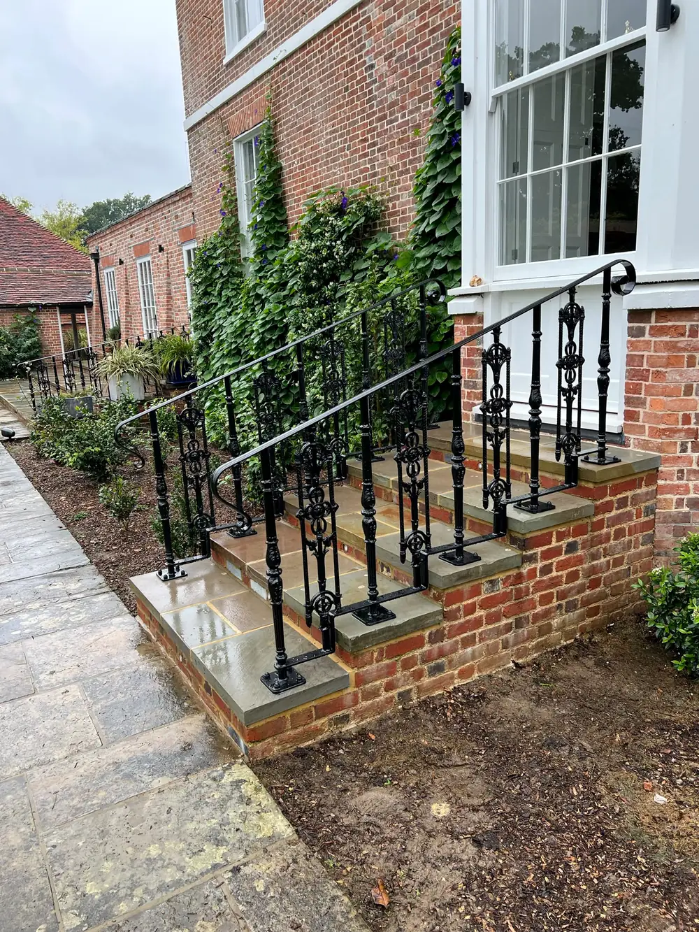 An ornate scrolled iron handrail on old brick steps