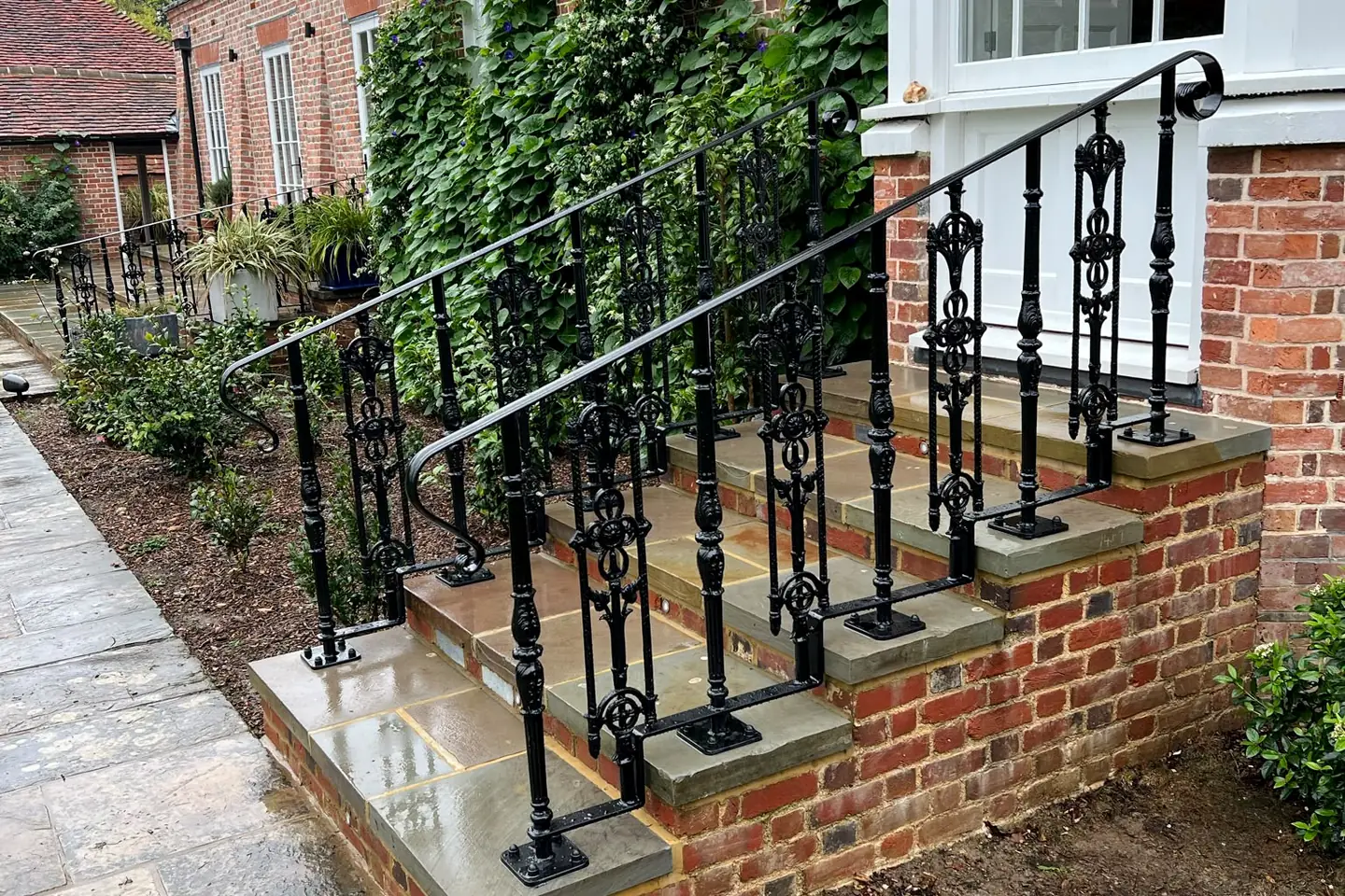 An ornate scrolled iron handrail on old brick steps